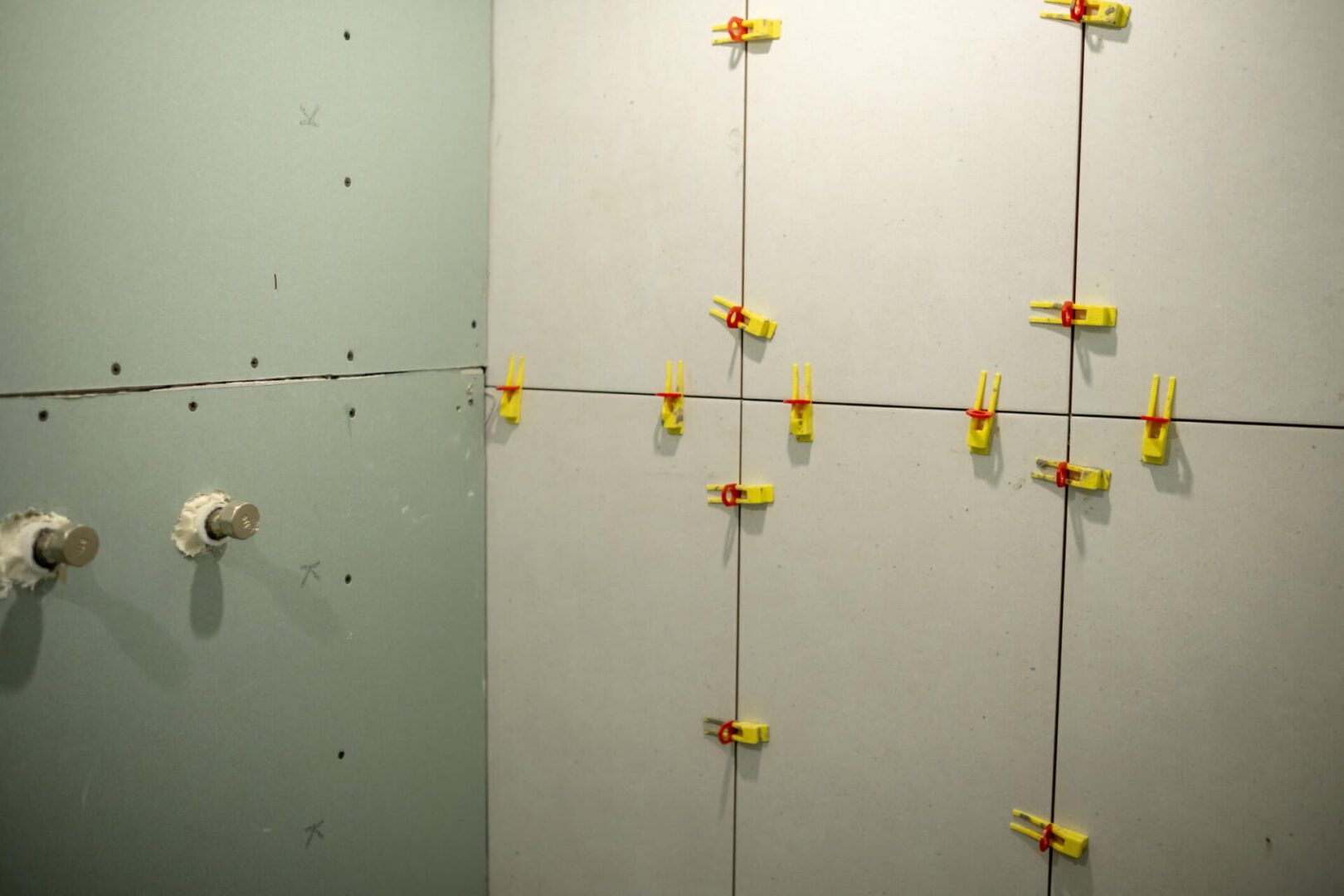 Bathroom wall tiles being installed with yellow spacers