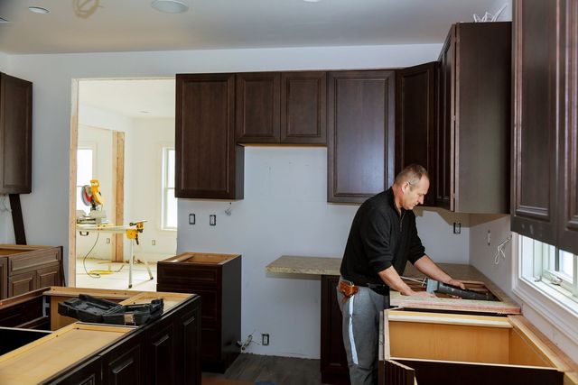 Contractor installing dark wood kitchen cabinets