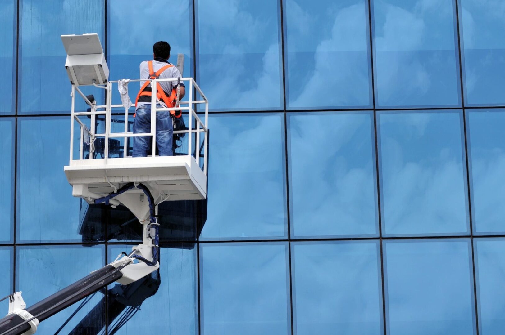 Window cleaner on lift washing glass facade