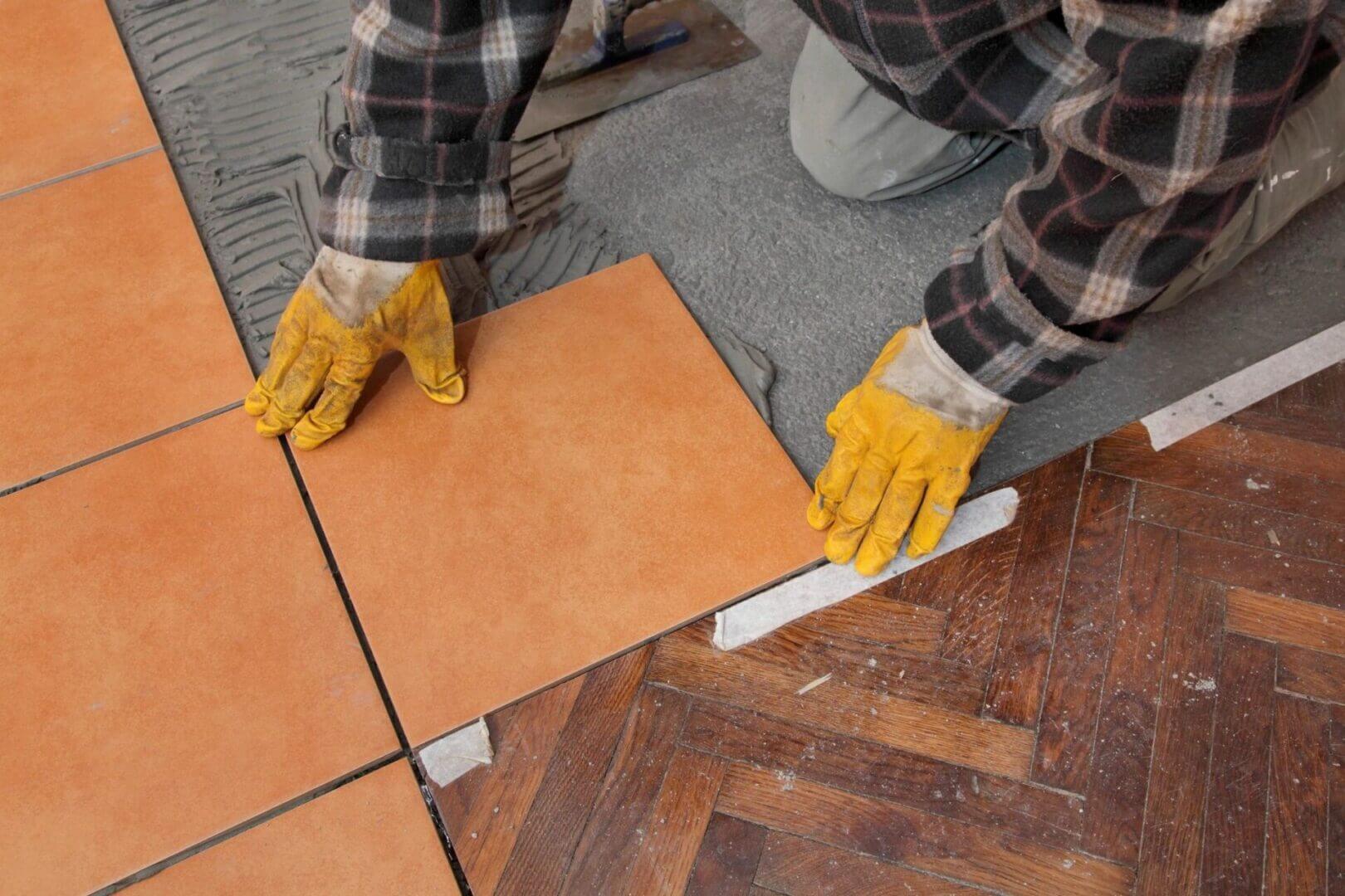 Worker installing terracotta floor tiles with gloves